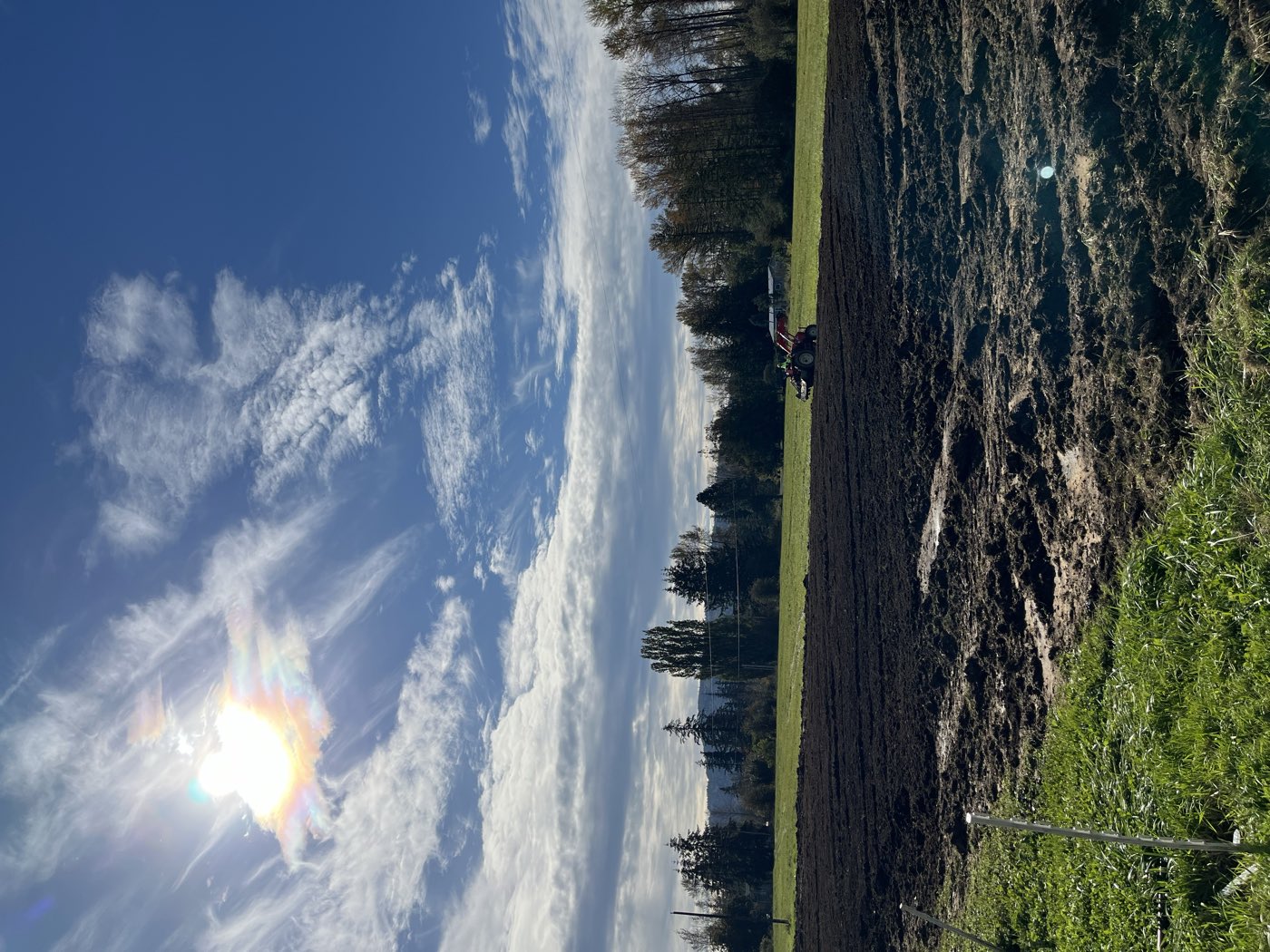 The tilled field under a wide sky, tractor working the far edge